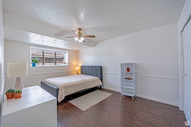 bedroom with dark wood-style floors, a textured ceiling, a ceiling fan, and baseboards