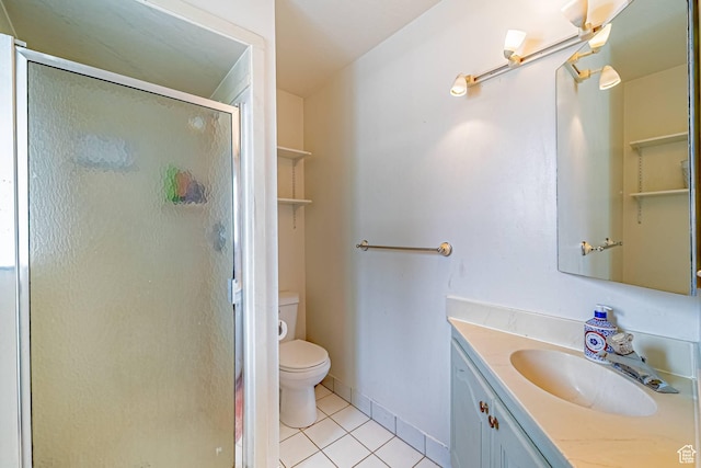 bathroom featuring toilet, a shower stall, vanity, baseboards, and tile patterned floors