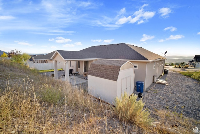 24 S 900 E, Hyde Park, UT 84318 - back of property with a shingled roof, an outdoor structure, fence, stucco siding, and a shed