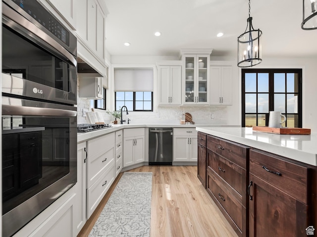 5351 S Lincoln Beach Rd, Spanish Fork, UT 84660 - kitchen with white cabinets, appliances with stainless steel finishes, light countertops, light wood-type flooring, and backsplash