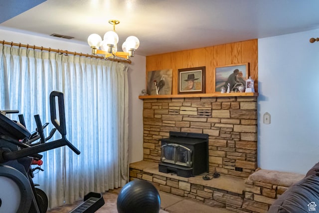 exercise area featuring a wood stove, visible vents, wood walls, and an inviting chandelier