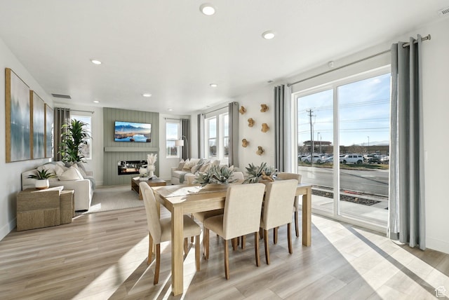 dining room featuring recessed lighting, a fireplace, and light wood-type flooring