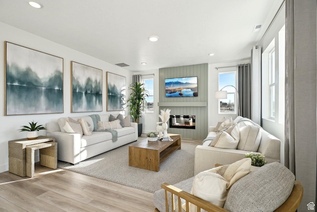 living room featuring wood finished floors, a fireplace, visible vents, and recessed lighting
