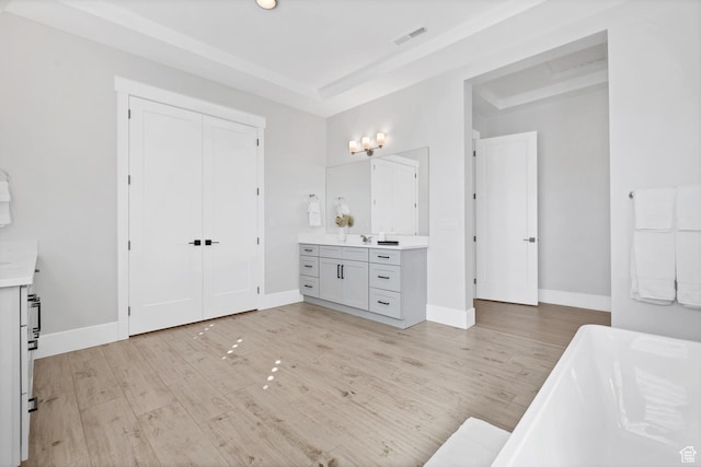 219 W Elinor Ln, Washington, UT 84780 - bathroom with visible vents, wood finished floors, a tray ceiling, vanity, and a freestanding tub