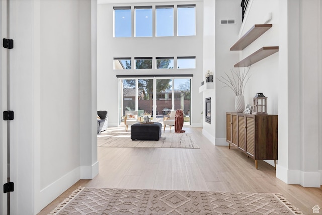 219 W Elinor Ln, Washington, UT 84780 - foyer featuring visible vents, a high ceiling, a glass covered fireplace, wood finished floors, and baseboards