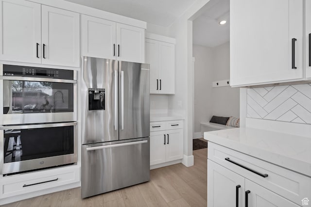219 W Elinor Ln, Washington, UT 84780 - kitchen with light wood finished floors, stainless steel appliances, tasteful backsplash, white cabinets, and light stone countertops