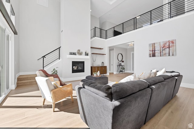 219 W Elinor Ln, Washington, UT 84780 - living area with a towering ceiling, a glass covered fireplace, wood finished floors, baseboards, and stairs