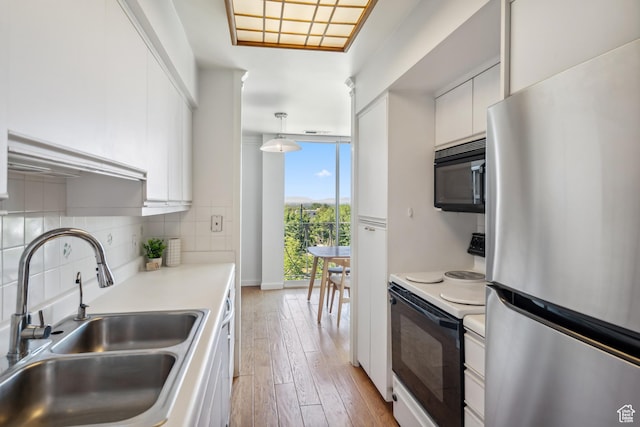 777 E S Temple S Unit 4A, Salt Lake City, UT 84102 - kitchen featuring freestanding refrigerator, black microwave, range with electric stovetop, white cabinetry, and decorative backsplash