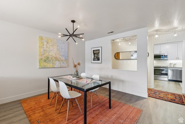 dining area with an inviting chandelier, light wood-type flooring, visible vents, and baseboards