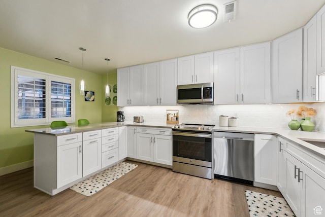 kitchen featuring stainless steel appliances, visible vents, a peninsula, and white cabinetry