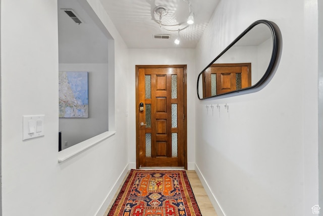 doorway with wood finished floors, visible vents, and baseboards