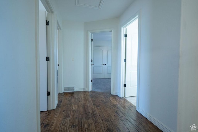 hall featuring dark wood-style floors, attic access, visible vents, and baseboards
