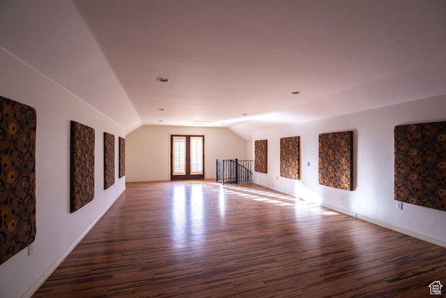 unfurnished living room with vaulted ceiling, wood finished floors, and baseboards