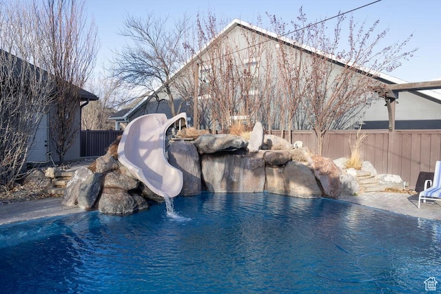 view of pool with a water slide, a swimming pool, and fence