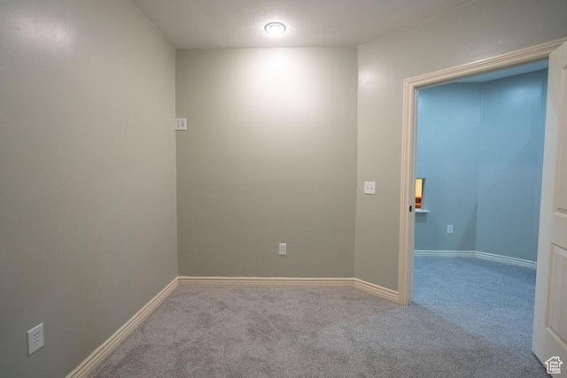 spare room with carpet floors, a textured ceiling, and baseboards