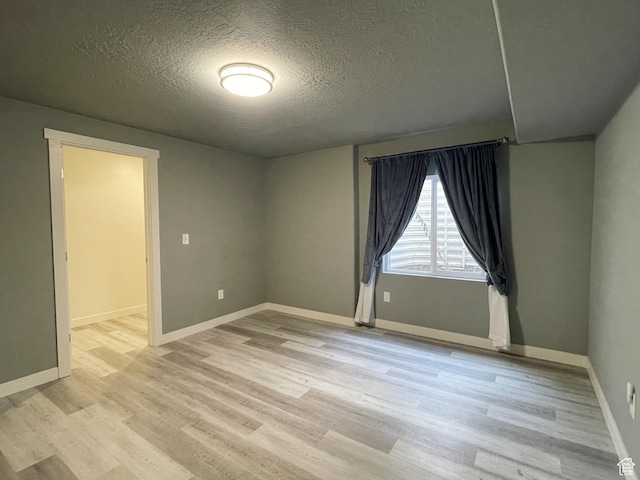 8416 N Sun Crest Dr, Eagle Mountain, UT 84005 - empty room with light wood-style flooring, baseboards, and a textured ceiling