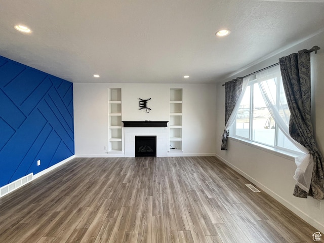 8416 N Sun Crest Dr, Eagle Mountain, UT 84005 - unfurnished living room with built in shelves, a fireplace, wood finished floors, and visible vents