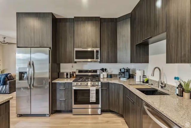 840 W Hilltop Ct, Francis, UT 84036 - kitchen featuring modern cabinets, appliances with stainless steel finishes, light stone counters, light wood-style floors, and a sink