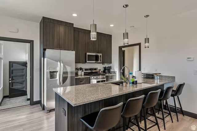 840 W Hilltop Ct, Francis, UT 84036 - kitchen with appliances with stainless steel finishes, light wood-style flooring, and a kitchen bar