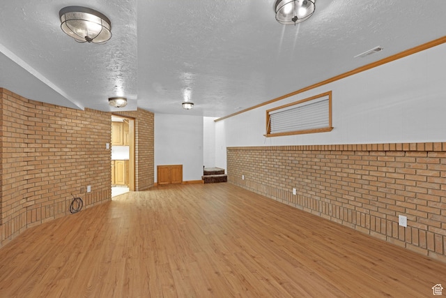 8693 S Vaquero Dr, Sandy, UT 84094 - unfurnished living room featuring stairway, wood finished floors, visible vents, brick wall, and a textured ceiling