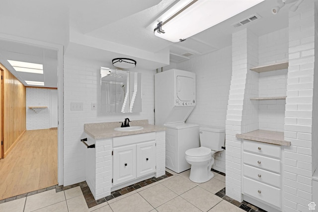 8693 S Vaquero Dr, Sandy, UT 84094 - bathroom featuring vanity, visible vents, stacked washer and dryer, tile patterned floors, and toilet