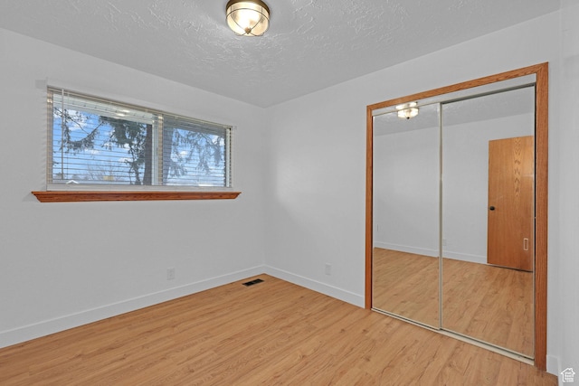 8693 S Vaquero Dr, Sandy, UT 84094 - unfurnished bedroom with wood finished floors, baseboards, visible vents, a closet, and a textured ceiling