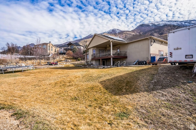 9575 Aztec Dr, Cedar Hills, UT 84062 - back of house with a trampoline, a mountain view, stucco siding, and a yard
