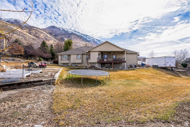 9575 Aztec Dr, Cedar Hills, UT 84062 - back of property featuring stucco siding, a trampoline, a mountain view, and a yard