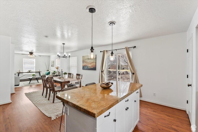 2419 N Nectar Way, Saratoga Springs, UT 84045 - kitchen featuring a kitchen island, wood finished floors, a textured ceiling, white cabinets, and hanging light fixtures