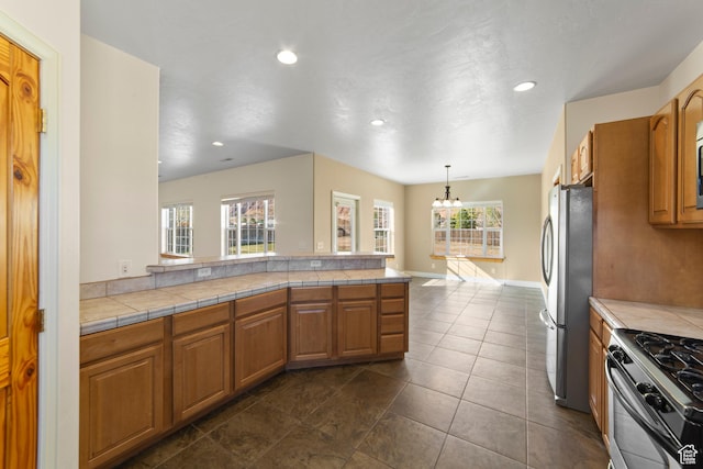 4224 Valle Del Sol, Moab, UT 84532 - kitchen featuring a peninsula, baseboards, appliances with stainless steel finishes, brown cabinetry, and decorative light fixtures