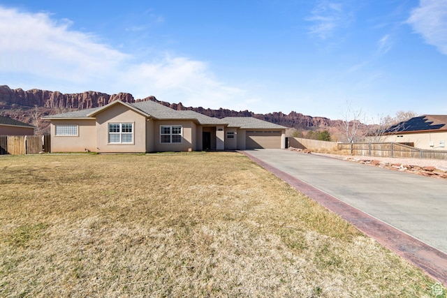 single story home with an attached garage, fence, a mountain view, a front lawn, and stucco siding