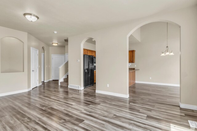 1351 Westbridge Cir, Provo, UT 84601 - unfurnished living room with a chandelier, wood finished floors, stairs, and arched walkways