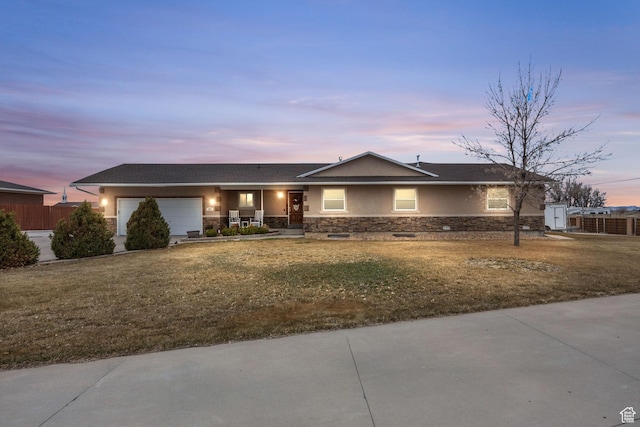 ranch-style home featuring stucco siding, stone siding, a porch, a yard, and a garage