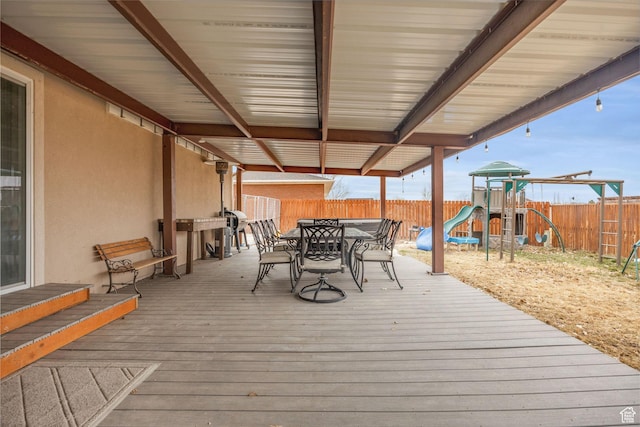 deck with a fenced backyard, playground community, and outdoor dining space
