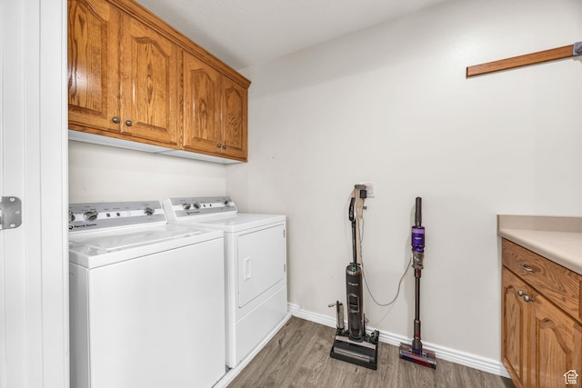 laundry room with separate washer and dryer, wood finished floors, cabinet space, and baseboards