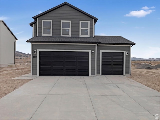 view of front of home featuring concrete driveway, a shingled roof, a mountain view, and an attached garage