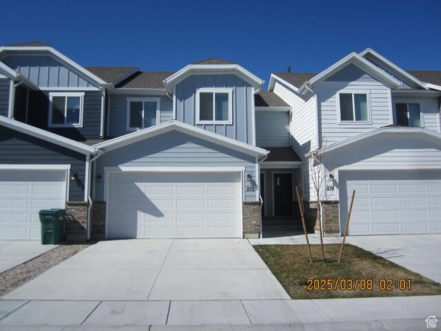 view of front of property featuring stone siding, board and batten siding, concrete driveway, and a garage