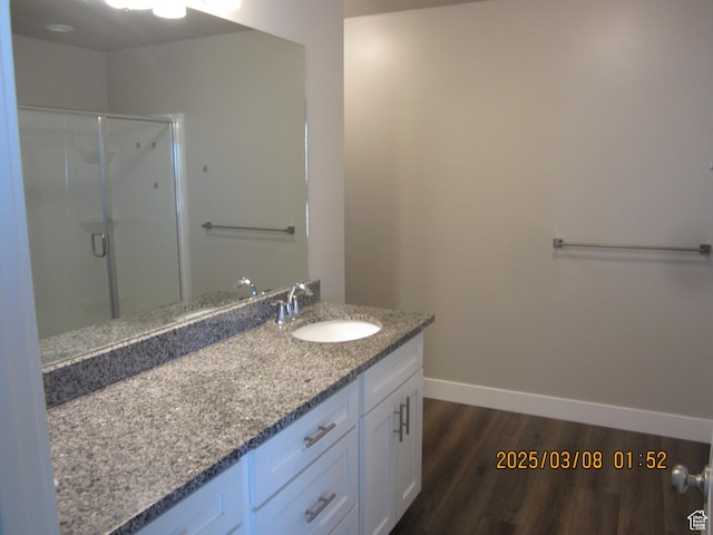 full bath featuring a shower stall, vanity, baseboards, and wood finished floors