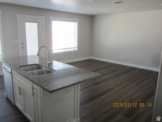kitchen with baseboards, a kitchen island with sink, a sink, dark wood-type flooring, and white cabinets