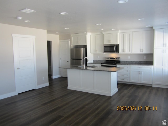 kitchen featuring an island with sink, a sink, stainless steel appliances, dark wood-type flooring, and white cabinetry