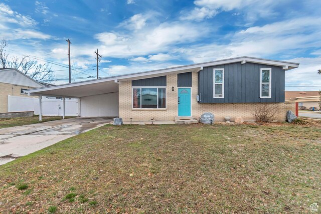 3734 S Bannock St, West Valley City, UT 84120 - view of front facade featuring driveway, brick siding, a carport, and a front yard