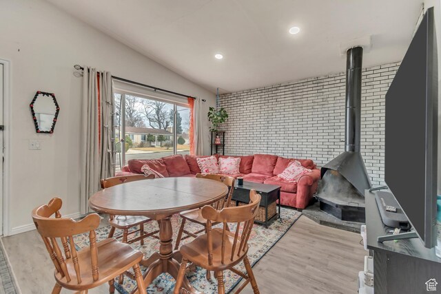 3734 S Bannock St, West Valley City, UT 84120 - dining area with light wood-style floors, lofted ceiling, a wood stove, and brick wall