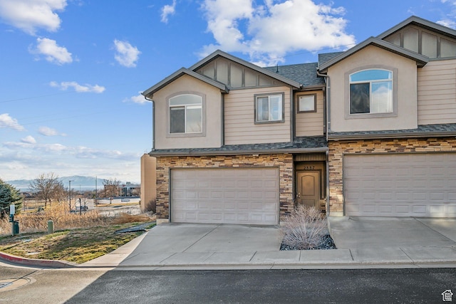 view of front facade featuring concrete driveway, stone siding, an attached garage, board and batten siding, and stucco siding