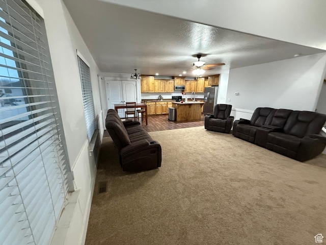 living room featuring carpet floors, a textured ceiling, and a ceiling fan