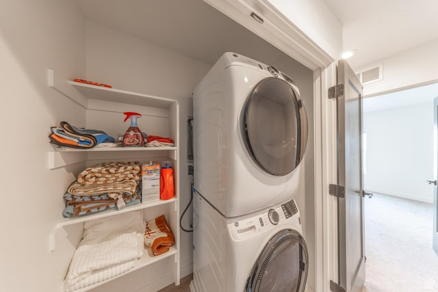 washroom with stacked washer / drying machine, laundry area, visible vents, and carpet