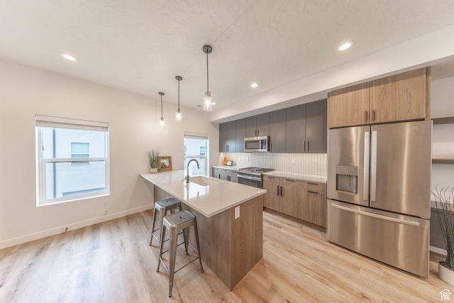 kitchen featuring stainless steel appliances, a breakfast bar, a sink, and light wood-style flooring