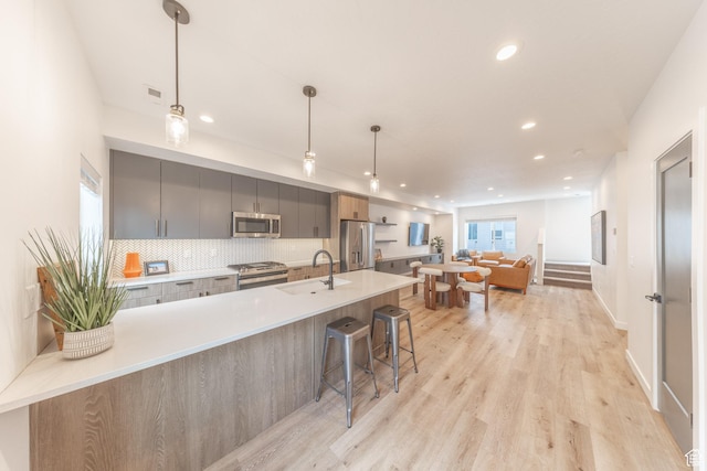 kitchen featuring a sink, appliances with stainless steel finishes, backsplash, gray cabinets, and modern cabinets