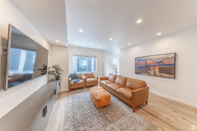 living area with light wood-type flooring, baseboards, a textured ceiling, and recessed lighting