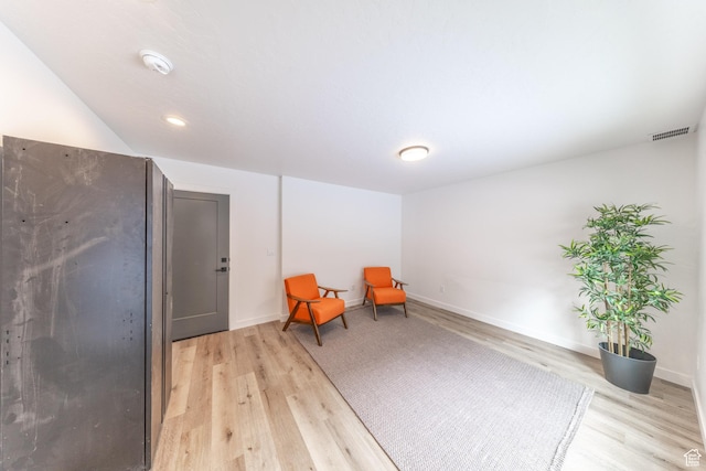 sitting room with light wood-style flooring, visible vents, and baseboards