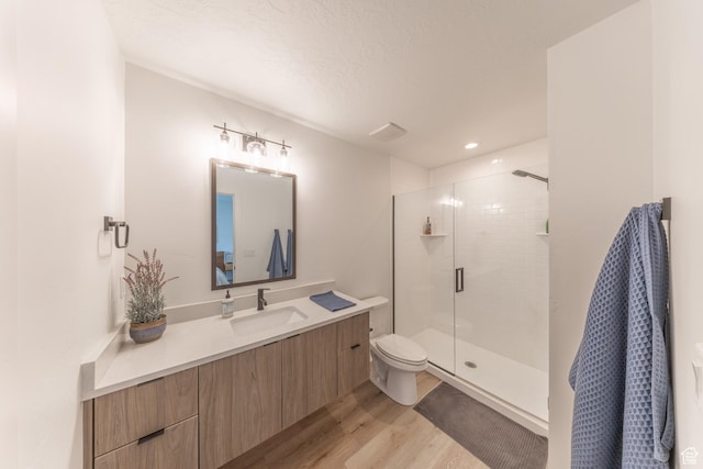 bathroom featuring toilet, a stall shower, wood finished floors, and vanity
